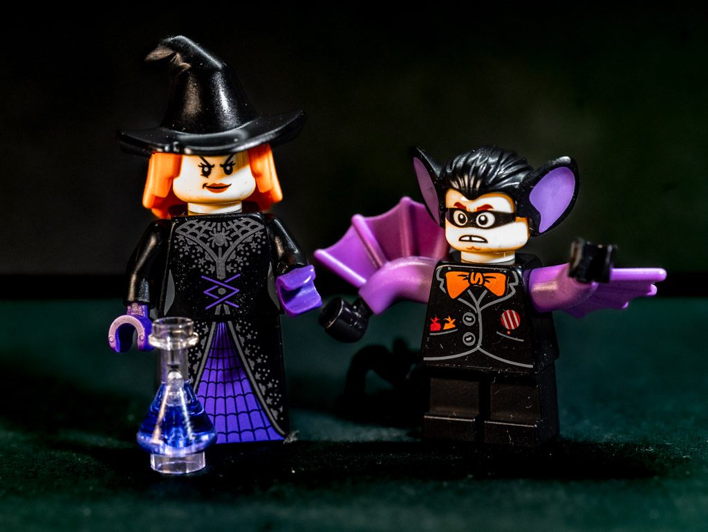 LEGO-Hexenfigur mit Zaubertrank und Vampirfigur mit Fledermausflügeln auf Tisch.