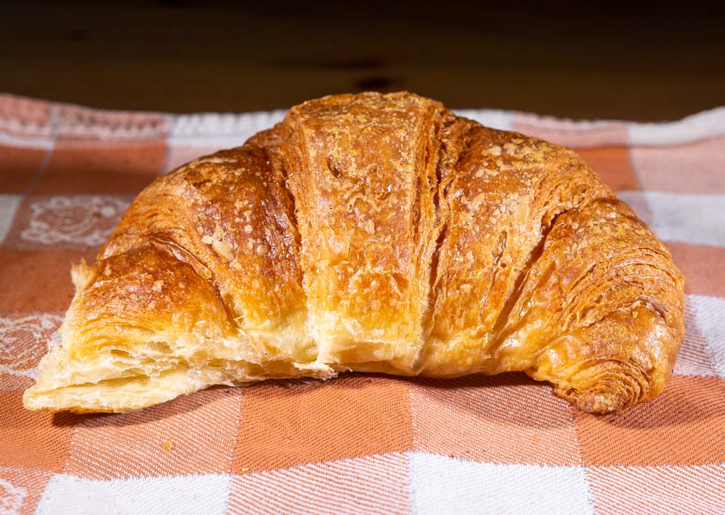 National Croissant Day - Tag des Croissants in den USA. Kuriose Feiertage - 30. Januar © 2022 Sven Giese - Bild 2 Ein knuspriges Croissant auf einer rot-weiß karierten Tischdecke.
