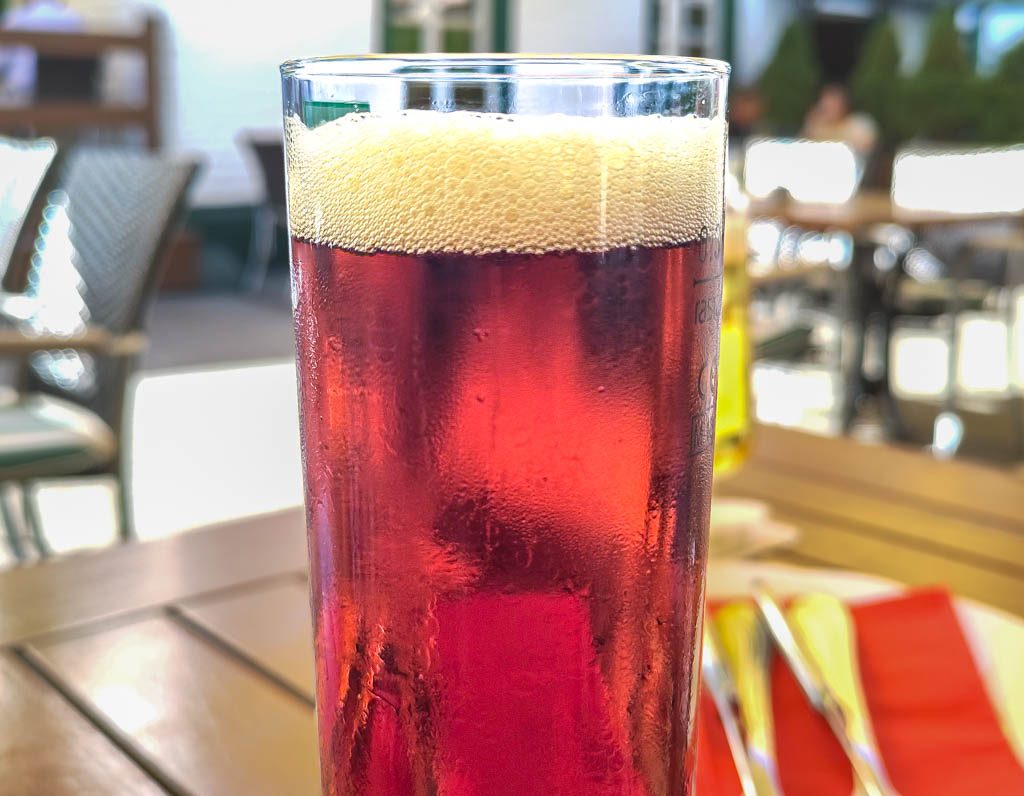 Glas mit schäumendem, dunklem Altbier auf Tisch im Außenbereich eines Cafés serviert.
