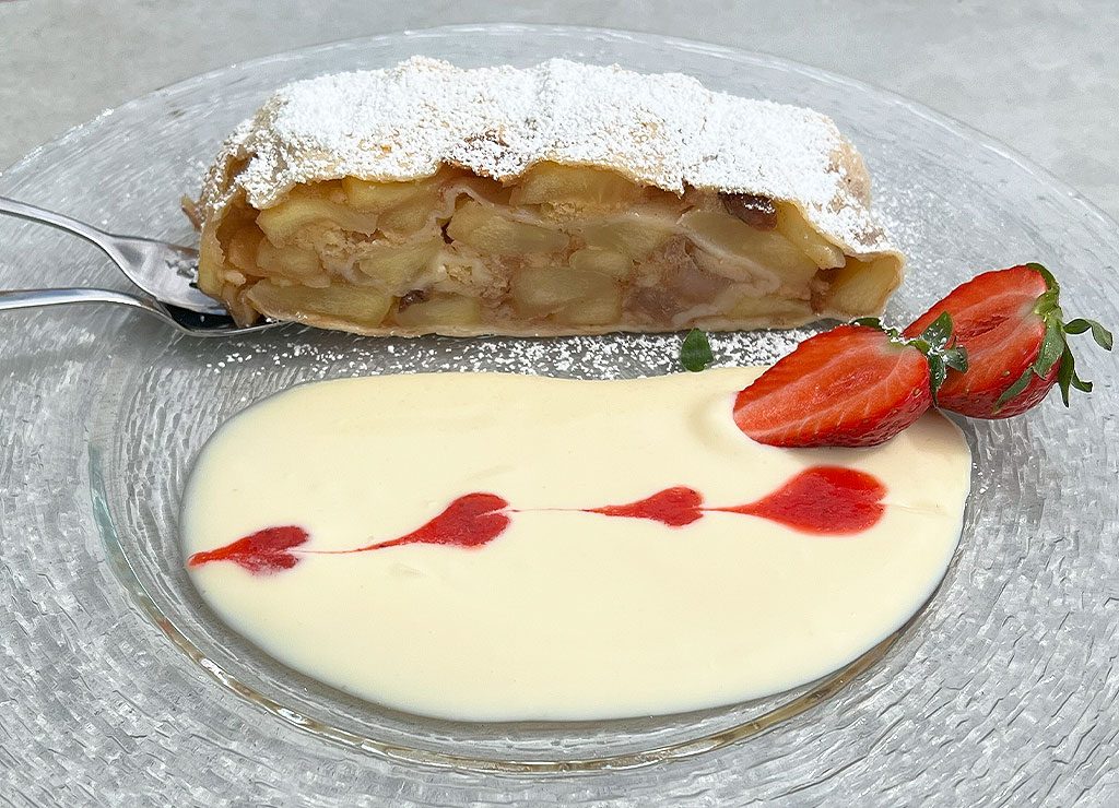 National Apple Strudel Day – Tag des Apfelstrudels in den USA. Kuriose Feiertage - 17. Juni © 2023 Dietmar Giese – Bild 3 Apfelstrudel mit Puderzucker, Vanillesauce und Erdbeeren, dekoriert mit Himbeersauce.