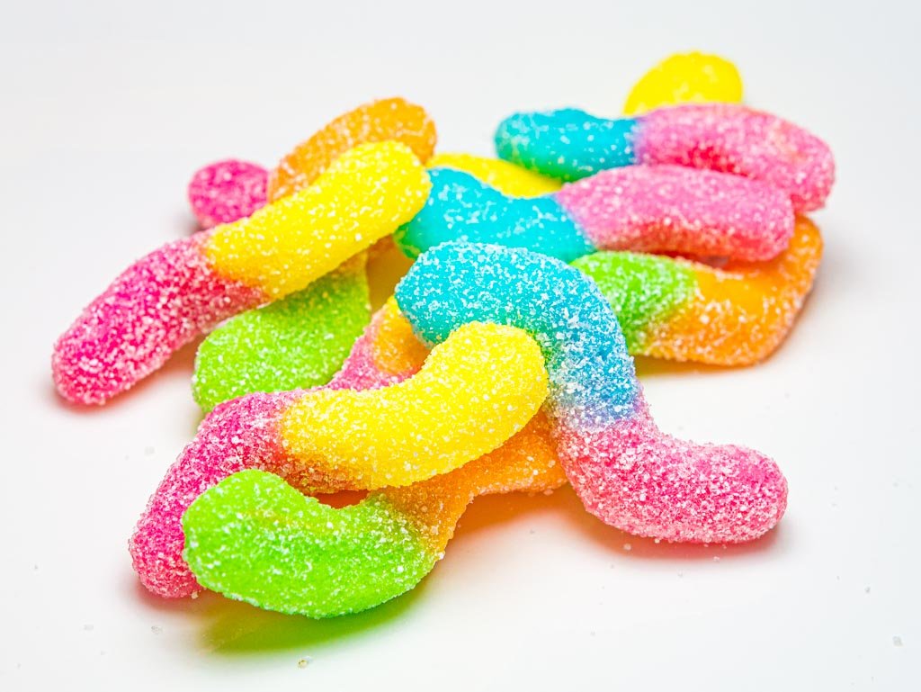 National Gummi Worm Day - Tag der Gummiwürmer in den USA. Kuriose Feiertage - 15. Juli © 2021 Sven Giese - Bild 3 Bunte, gezuckerte Gummiwürmer liegen gemischt auf weißem Teller oder Untergrund.