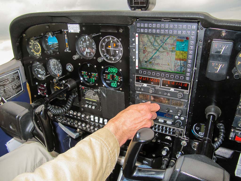 National Aviation Day - Nationaler Tag der Luftfahrt in den USA. Kuriose Feiertage - 19. August © 2019 Sven Giese - Bild 1 Cockpit eines Motorflugzeugs mit einer Hand, die die Instrumente bedient.
