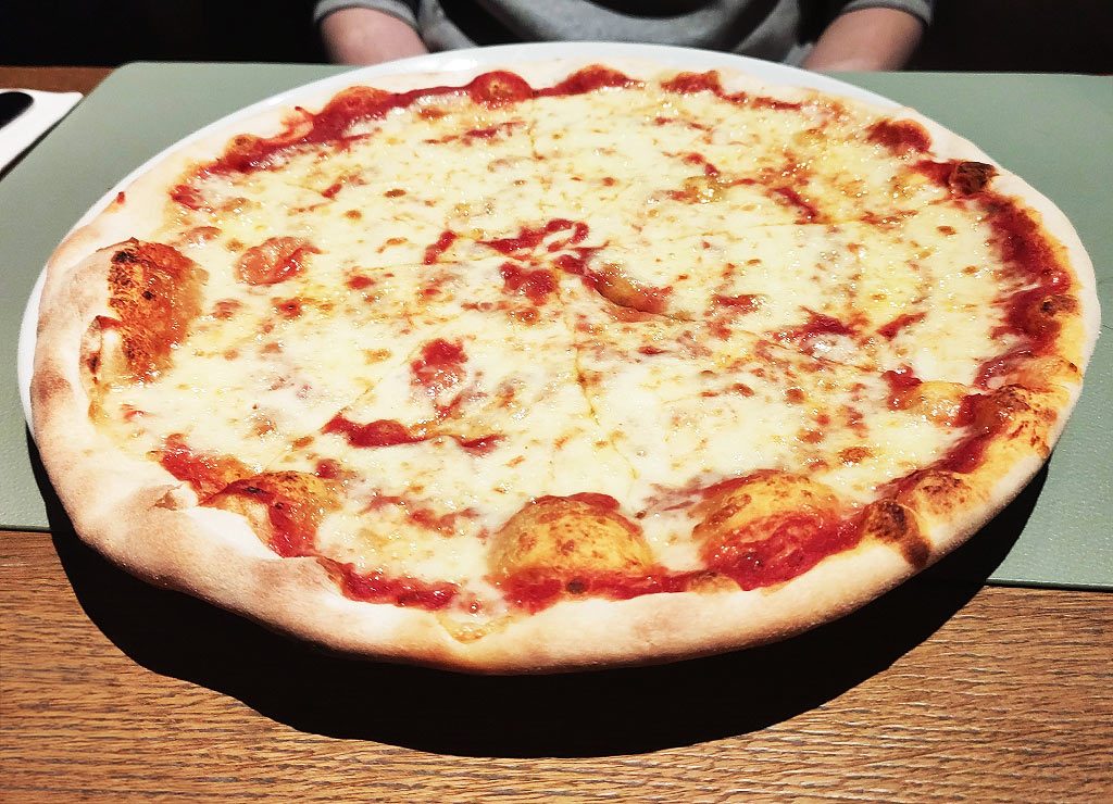 Margherita-Pizza mit Tomatensauce und geschmolzenem Käse auf dünnem Teig in einem Restaurant serviert.
