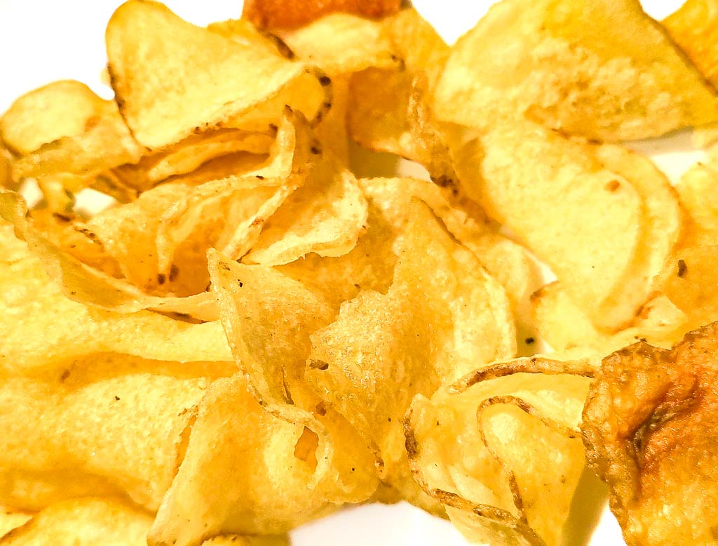 Nahaufnahme von knusprigen Kartoffelchips mit leicht gewellten Rändern und goldener Farbe.