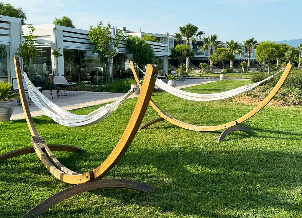 Hammock Day – Tag der Hängematte in den USA. Kuriose Feiertage - 22. Juli © 2024 Dietmar Giese – Bild 2 Zwei moderne Hängematten mit Holzgestell auf grünem Rasen vor einem Hotelgebäude.
