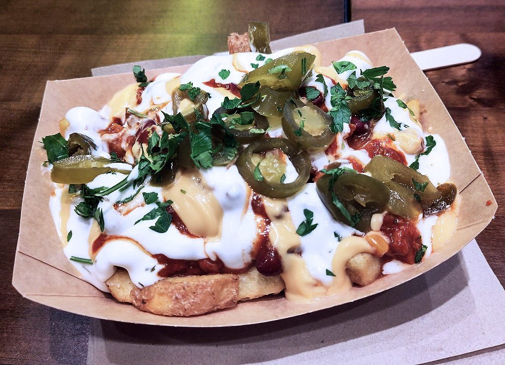 National French Fries Day – Pommes-Tag in den USA. Kuriose Feiertage – 13. Juli © 2026 Sven Giese – Bild 2 Pommes frites mit Käse-, Joghurt- und Chilisauce, Jalapeños und frischen Kräutern in Pappschale.