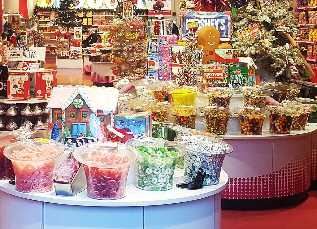 National Candy Day - Tag der Süßigkeiten in den USA. Kuriose Feiertage - 4. November © 2021 Sven Giese - Bild 2 Bunte Süßigkeiten und Weihnachtsdekoration in einem Süßwarenladen mit festlicher Atmosphäre.