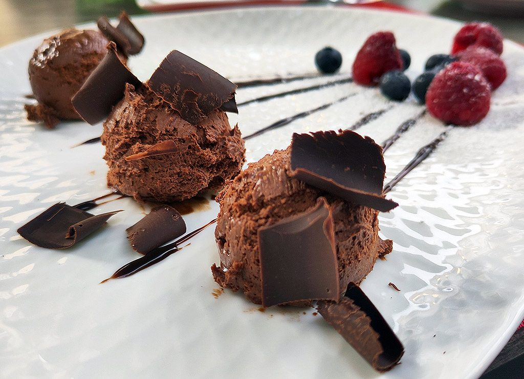 National Chocolate Mousse Day – Tag der Schokoladenmousse in den USA. Kuriose Feiertage - 3. April © 2025 Sven Giese – Bild 1 Drei Nocken Schokoladenmousse mit Schokoraspeln, garniert mit Himbeeren und Blaubeeren.