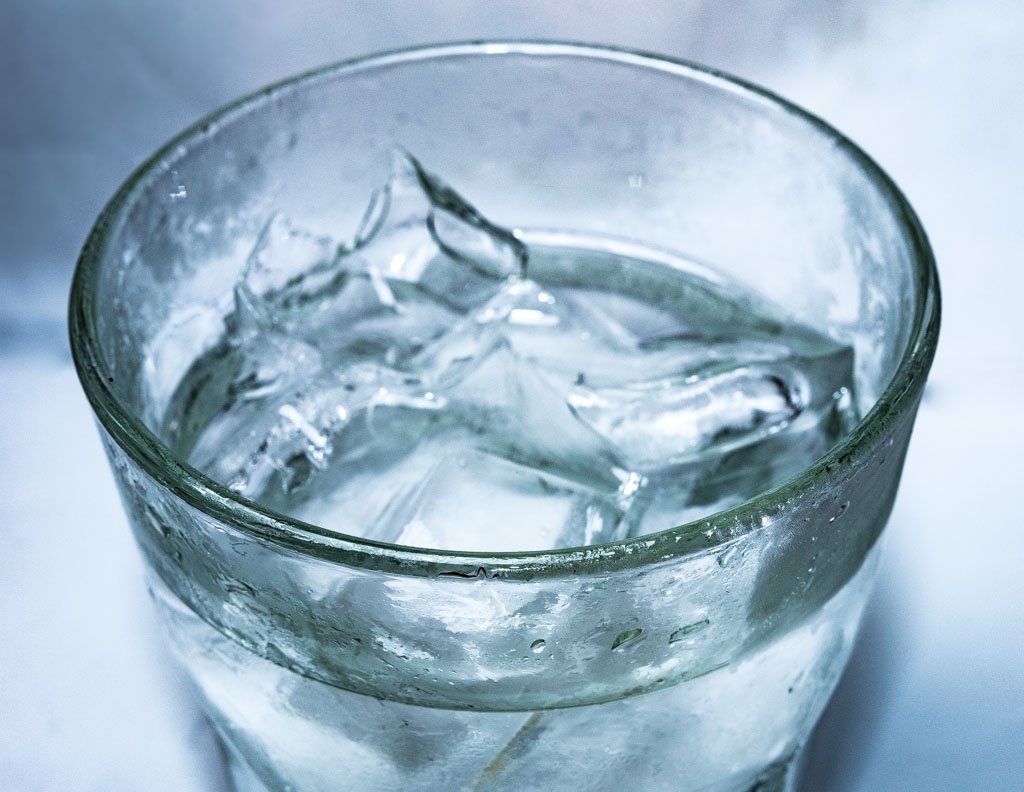National Refreshment Day - Tag der Erfrischungen in den USA. Kuriose Feiertage - vierter Donnerstag im Juli © 2020 Sven Giese Ein großes Glas mit Eiswürfeln, außen mit Kondenswasser, vor hellem Hintergrund.
