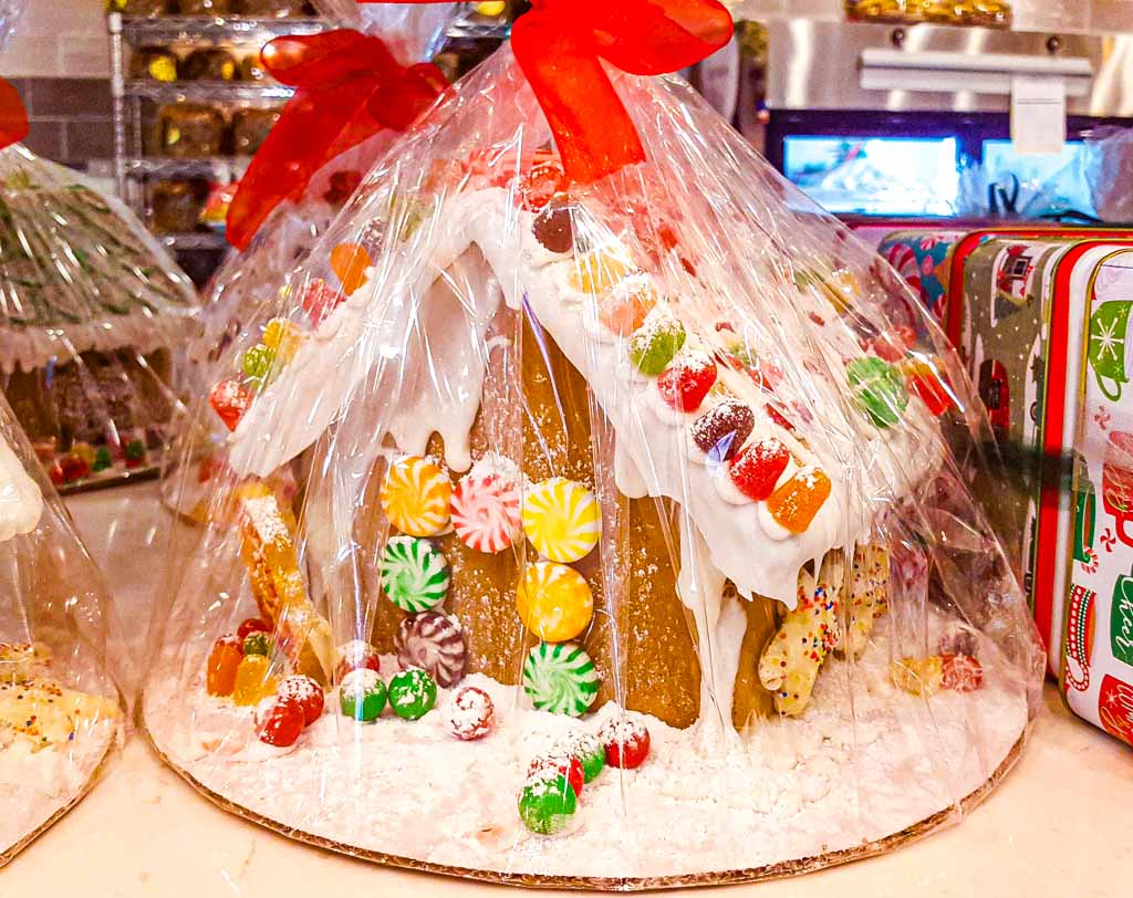 Lebkuchenhaus mit bunten Süßigkeiten dekoriert, in transparenter Folie mit roter Schleife verpackt.