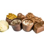 Verschiedene Pralinen mit Nüssen, Schokolade und weißer Glasur auf weißem Hintergrund.