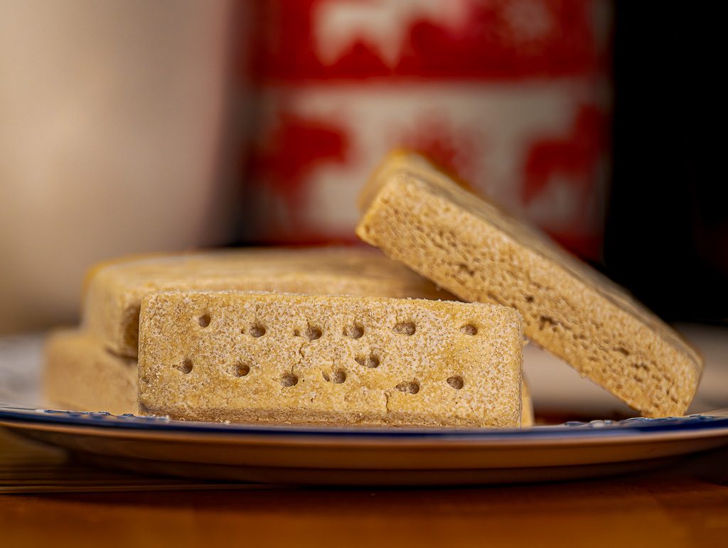 National Shortbread Day - Tag des schottischen Shortbread in den USA. Kuriose Feiertage - 6. Januar © 2026 Sven Giese - Bild 3 Gestapelte Shortbread-Riegel auf Teller, goldbraun gebacken, mit Löchern und weicher Krume im Vordergrund.