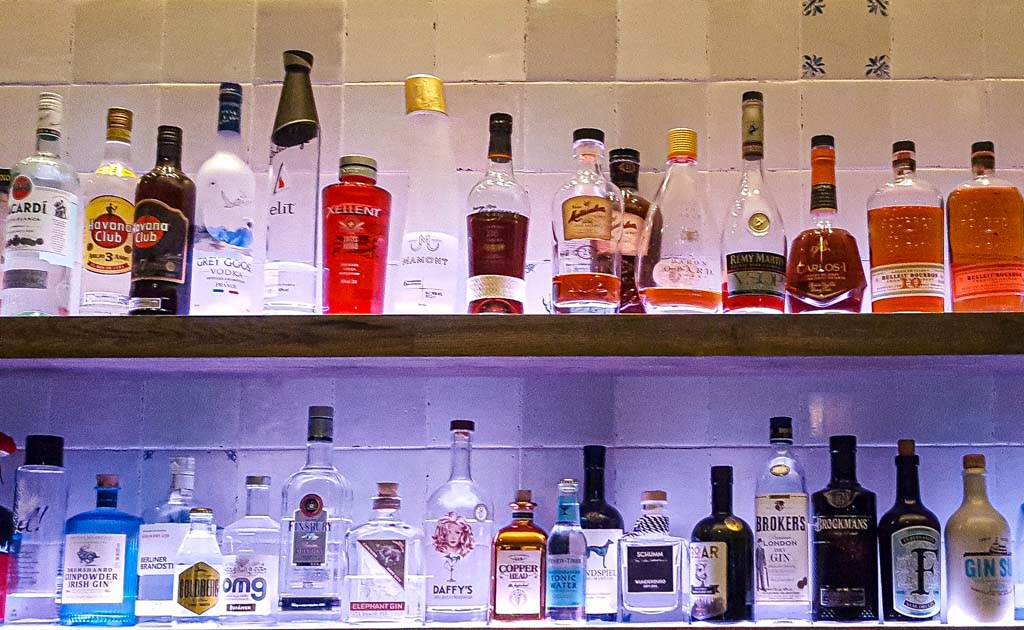 World Bartender Day - Welttag der Barkeeper. Kuriose Feiertage - 24.Februar © 2020 Sven Giese - Bild 2 Ein beleuchtetes Barregal mit verschiedenen Flaschen von Spirituosen, darunter Gin, Whisky und Rum.