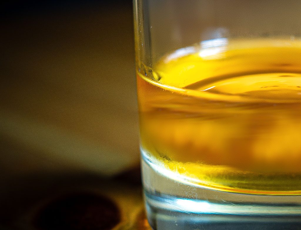 Nahaufnahme eines Whiskyglases mit goldener Flüssigkeit auf unscharfem Hintergrund.