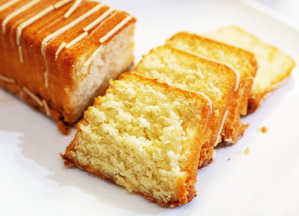 Ein Rührkuchen mit mehreren goldbraunen Scheiben, mit einer dünnen Glasur verziert.