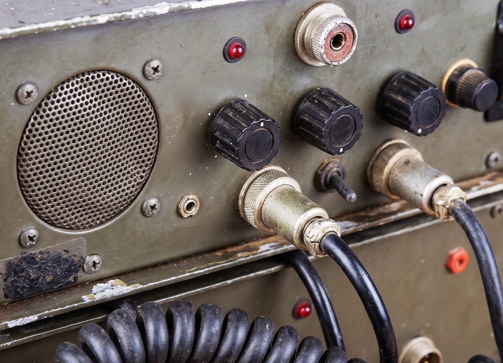 World Amateur Radio Day - Weltamateurfunktag. Kuriose Feiertage - 18. April © 2026 Sven Giese Nahaufnahme alter Funktechnik mit Drehknöpfen, Lautsprecher, Steckern und Kabeln im Metallgehäuse.