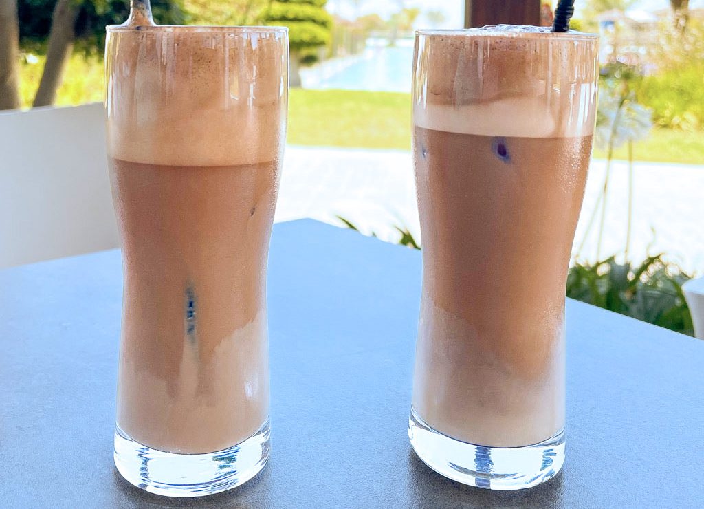 National Coffee Milkshake Day – Kaffee-Milchshake-Tag in den USA. Kuriose Feiertage - 26. Juli © 2023 Sven Giese Zwei Gläser mit schaumigem Eiskaffee auf einem Tisch mit Ausblick.