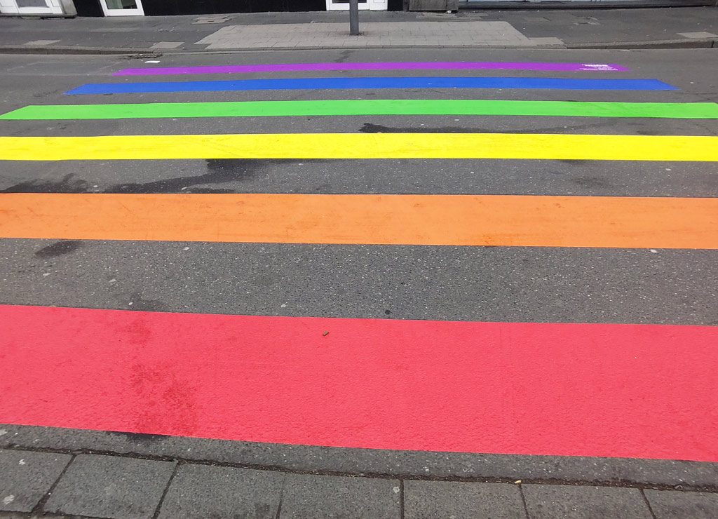 Tag des Zebrastreifens in Deutschland. Kuriose Feiertage - 1. September © 2024 Sven Giese – Bild 2 Ein Zebrastreifen auf einer Straße, der in den Farben des Regenbogens bemalt ist.