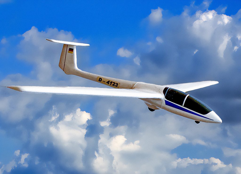 Weißes Modellsegelflugzeug mit deutscher Kennung vor leicht bewölktem Himmel.