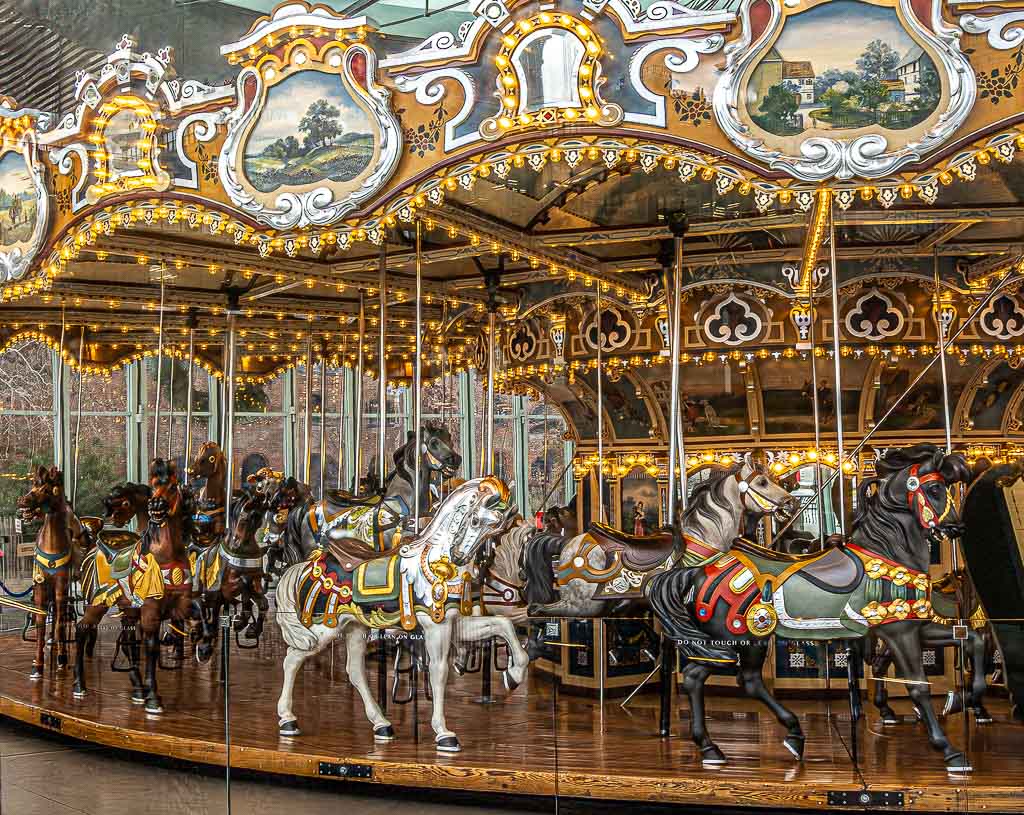 Jane's Carousel in Brooklyn, New York. Tag des Karussells in den USA © 2025 Sven Giese – Bild 2 Detailaufnahme eines reich verzierten Karussells mit geschnitzten Pferden und Lichtern im Kreis.