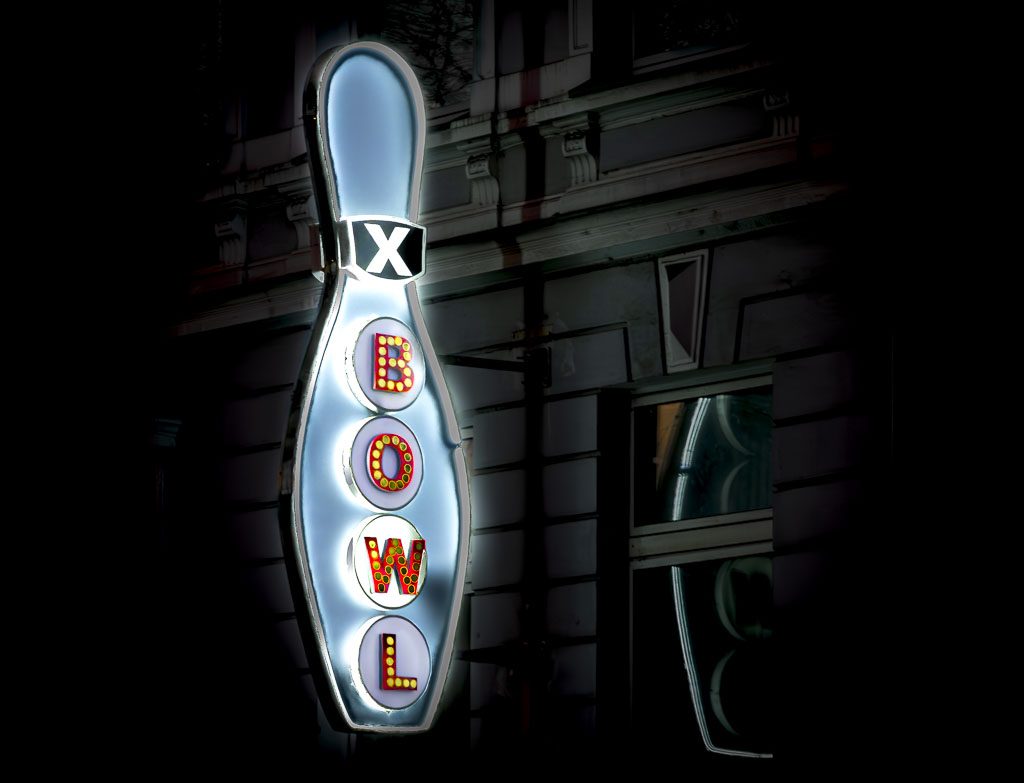 National Bowling Day – Tag des Bowlings in den USA. Kuriose Feiertage – zweiter Samstag im August © 2025 Sven Giese Beleuchtete Neon-Reklame für eine Bowling-Bahn an der Fassade eines nächtlichen Gebäudes.