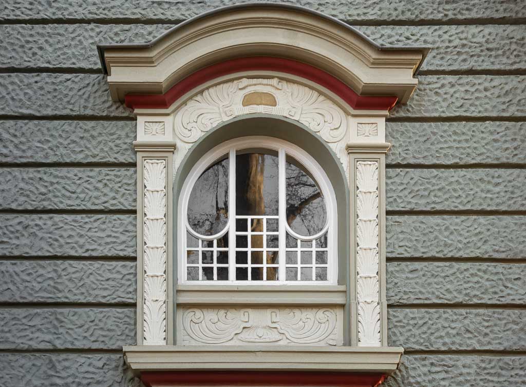 World Art Nouveau Day – Weltjugendstiltag. Kuriose Feiertage - 10. Juni © 2024 Sven Giese - Bild 1 Jugendstil-Fenster mit weißen Ornamenten und rundem oberen Abschluss.