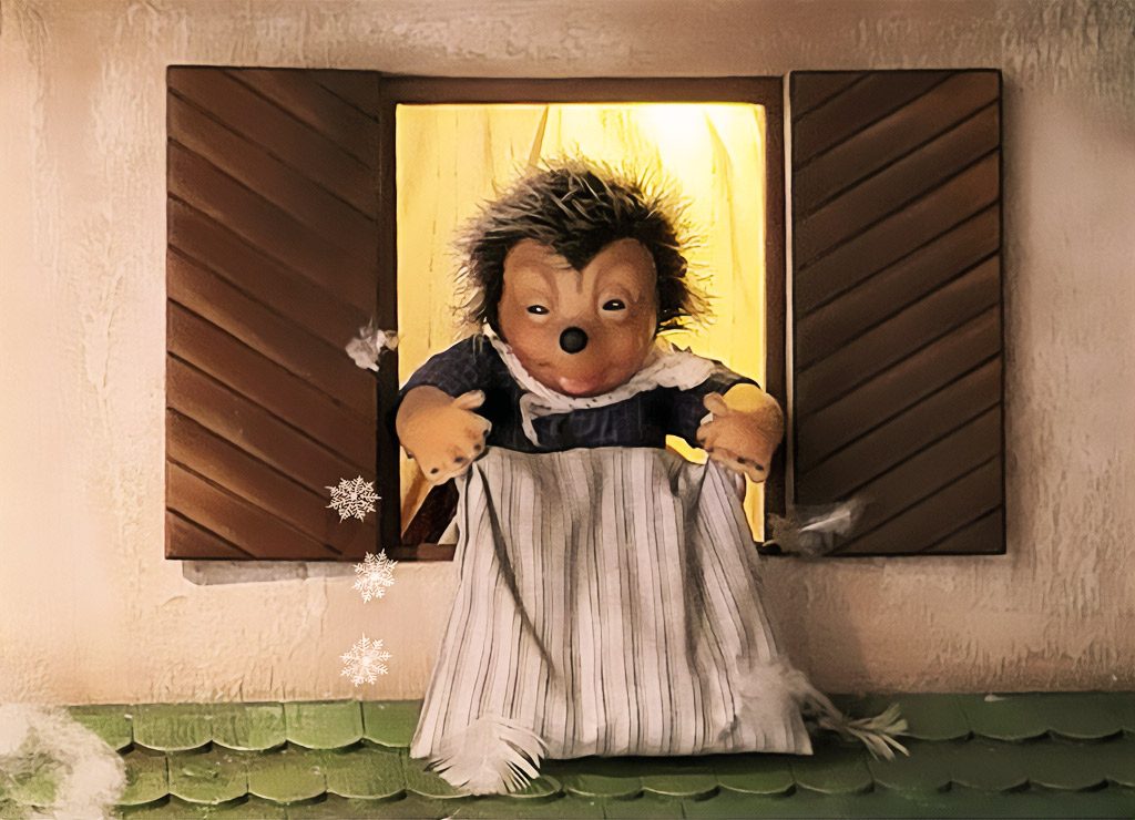 Tag der Frau Holle oder: das Ende der Rauhnächte am 6. Januar. Kuriose Feiertage - 6. Januar © 2025 Sven Giese – Bild 2 Eine Igel-Figur in einem Fenster stellt Frau Holle dar, die Federn und Schnee aus einem Sack schüttelt.