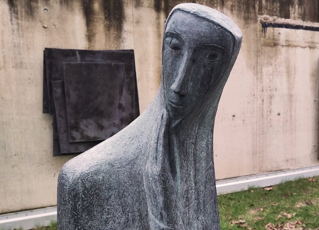 Abstrakte Statue einer Figur, die nachdenklich ihren Kopf auf ihre Hand stützt.