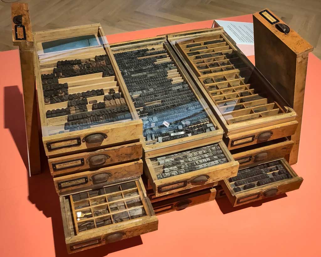  Alte Holzsetzkästen mit Bleilettern in offenen Schubladen, ausgestellt in einem Museum.