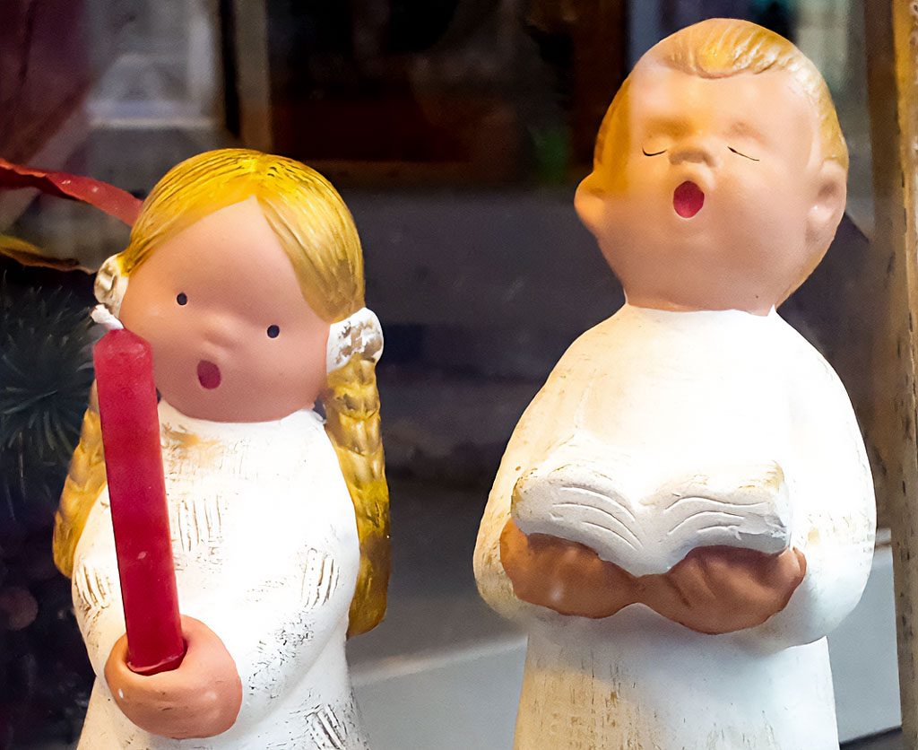 Zwei Figuren: Mädchen mit Kerze und Junge mit Buch, als Chorsänger dargestellt.