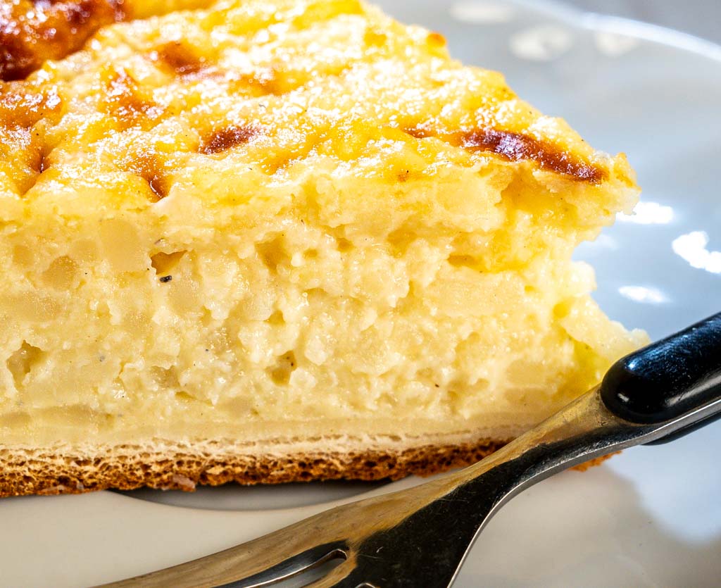 Ein Stück Reisfladen auf Teller mit Gabel, Oberfläche goldbraun und saftig gebacken.