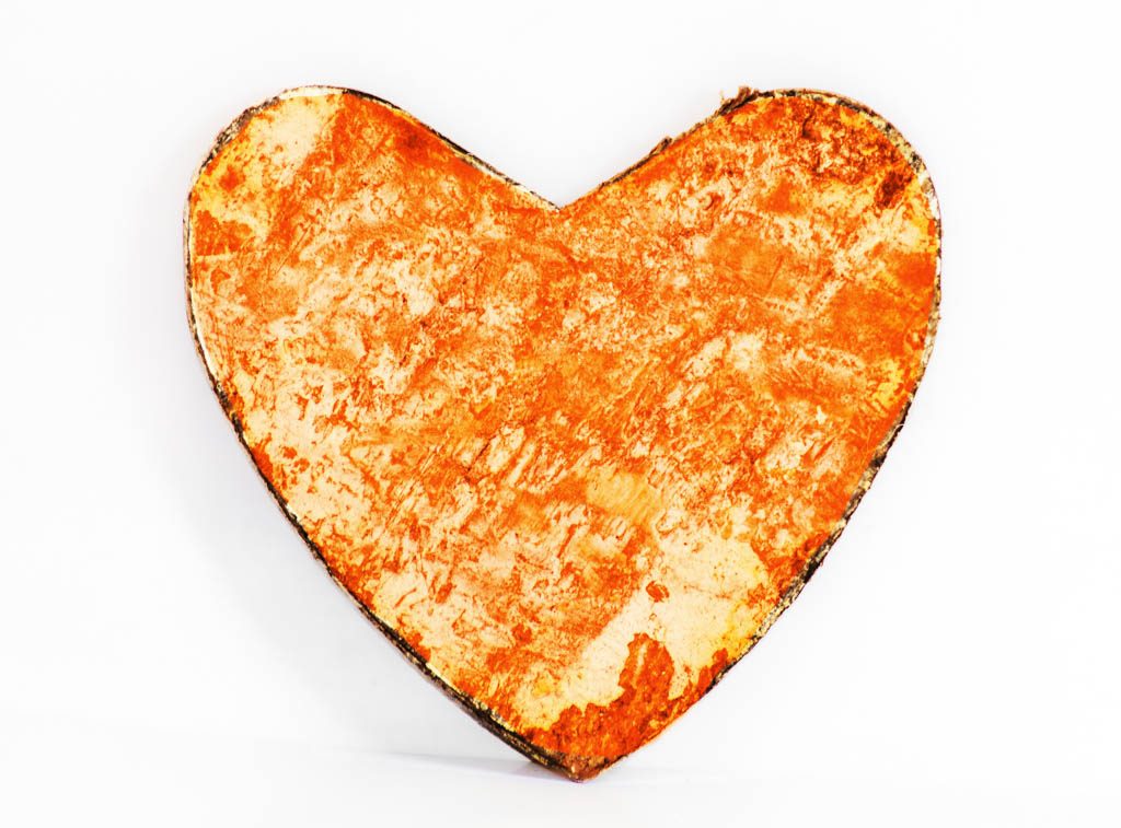 Ein grob bemaltes, orange-rötliches Herz aus Holz auf weißem Hintergrund, leicht schattiert.