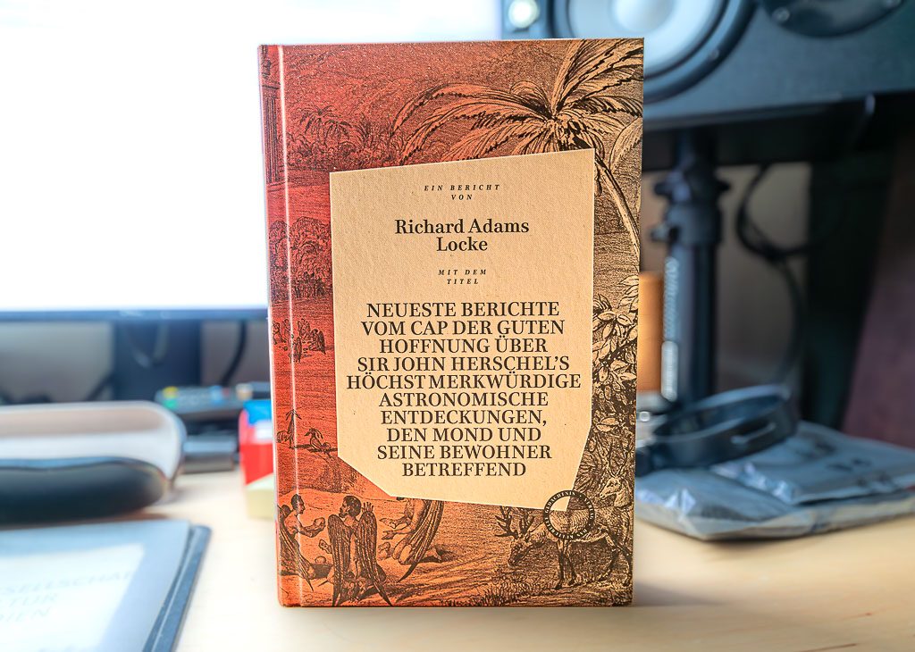 The Great Moon Hoax oder der Tag des großen Mondschwindels am 25. August 1835. Kuriose Feiertage © 2025 Sven Giese - Bild 2 Buch mit historischem Titelblatt über den Mondschwindel von Richard Adams Locke, auf Tisch.