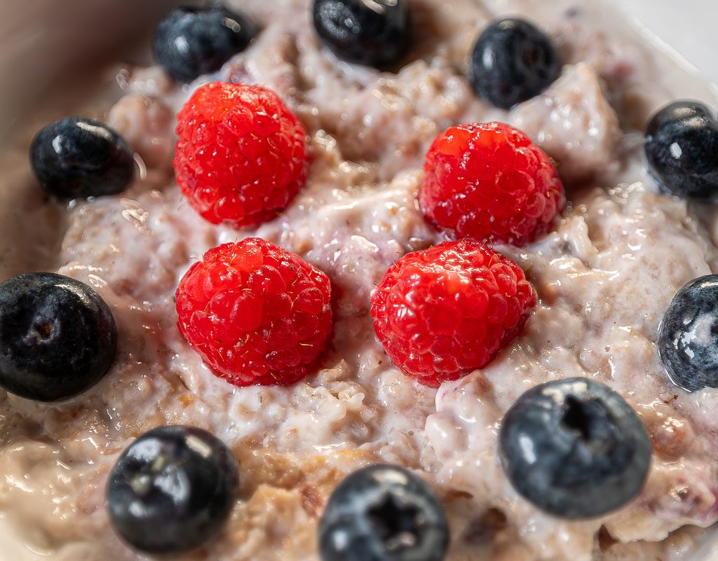 World Porridge Day – Welttag des Porridge. Kuriose Feiertage – 10. Oktober © 2025 Sven Giese - Bild 2 Nahaufnahme von Porridge: leuchtende Himbeeren und Blaubeeren auf cremiger Haferbasis, detailliert fotografiert.