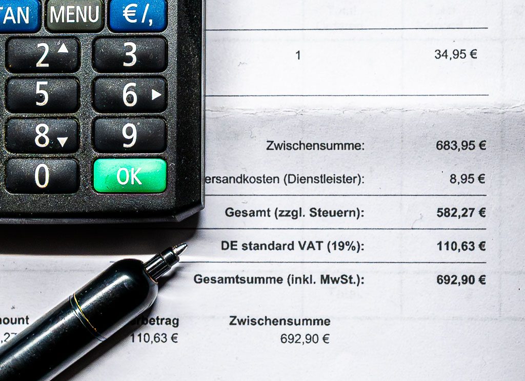 Bild 50: Taschenrechner und Stift auf Rechnung mit Mehrwertsteuer, Zwischensumme und ausgewiesenem Gesamtbetrag in Euro.