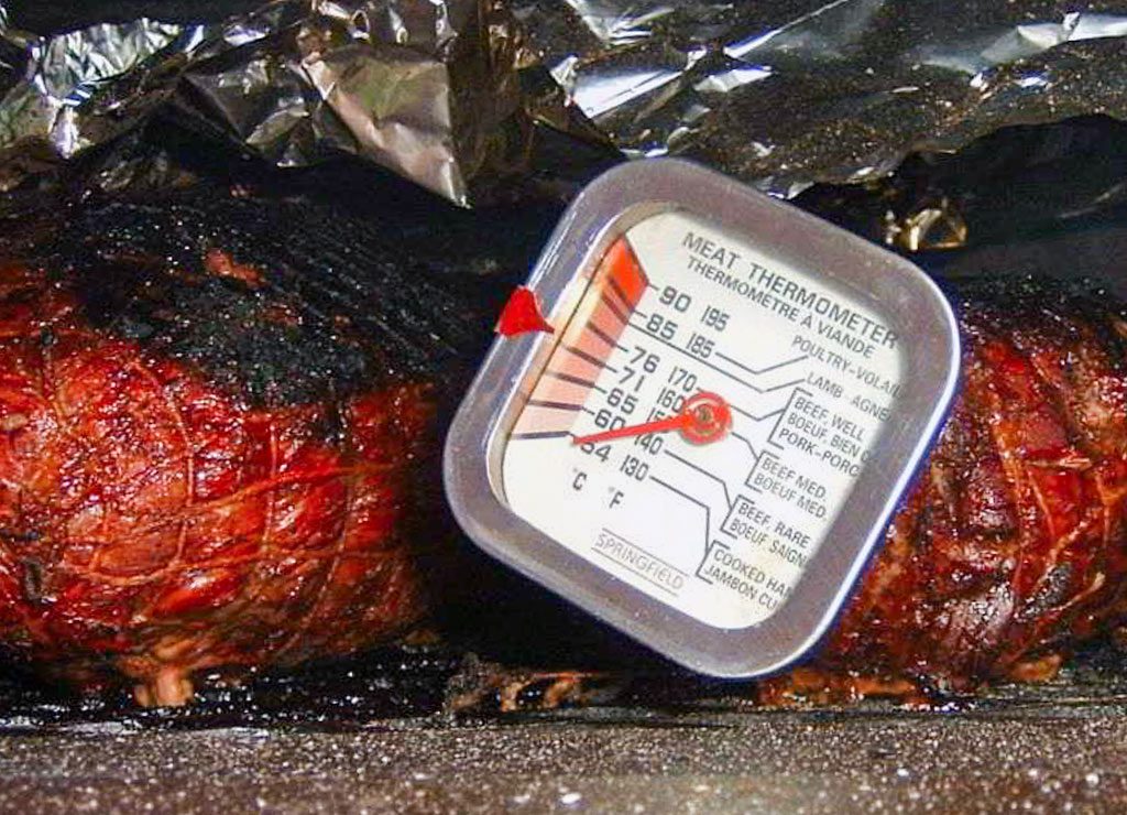 National Pulled Pork Day – der US-amerikanische Tag des Pulled Pork. Kuriose Feiertage – 12. Oktober (c) 2026 Sven Giese – Bild 2 Gegrilltes Schweinefleisch mit dunkler Kruste und Fleischthermometer in einer Bratform.