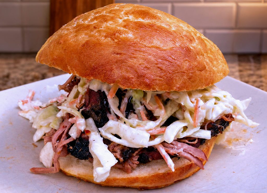 National Pulled Pork Day – der US-amerikanische Tag des Pulled Pork. Kuriose Feiertage – 12. Oktober (c) 2026 Sven Giese – Bild 3 Pulled-Pork-Burger mit goldbraunem Brötchen, gezupftem Fleisch und cremigem Krautsalat.